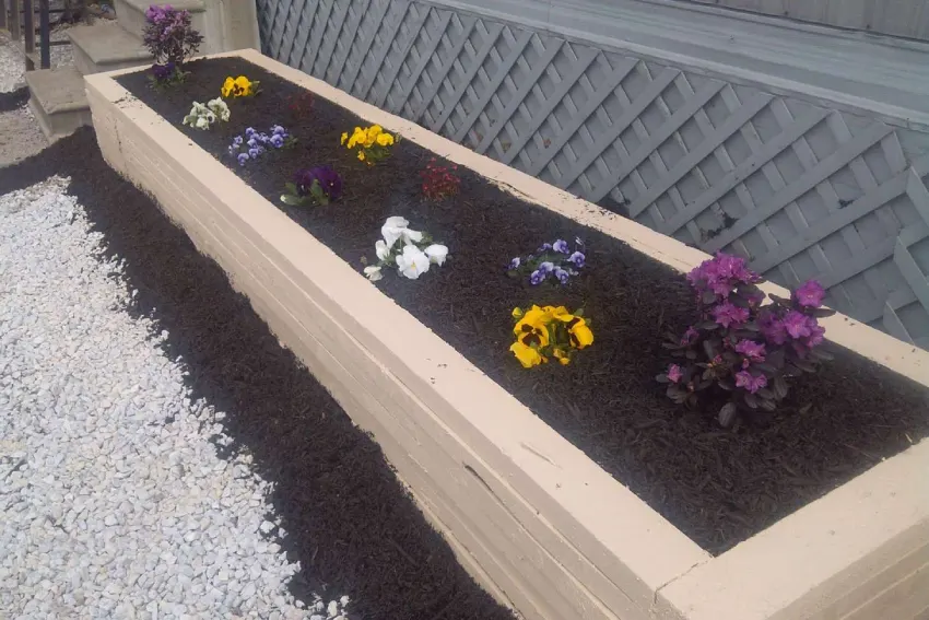 A long planter filled with flowers on top of gravel.