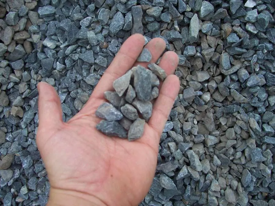 A hand holding some rocks in the dirt